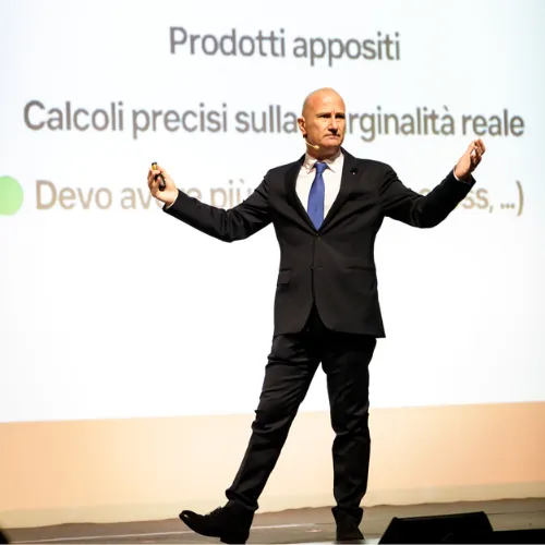 Riccardo Fagioli sul palco davanti a una slide sui calcoli di marginalità